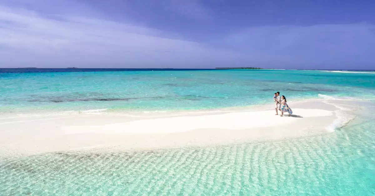 Aerial view of a couple walking on a picturesque sandbar in crystal-clear turquoise waters.