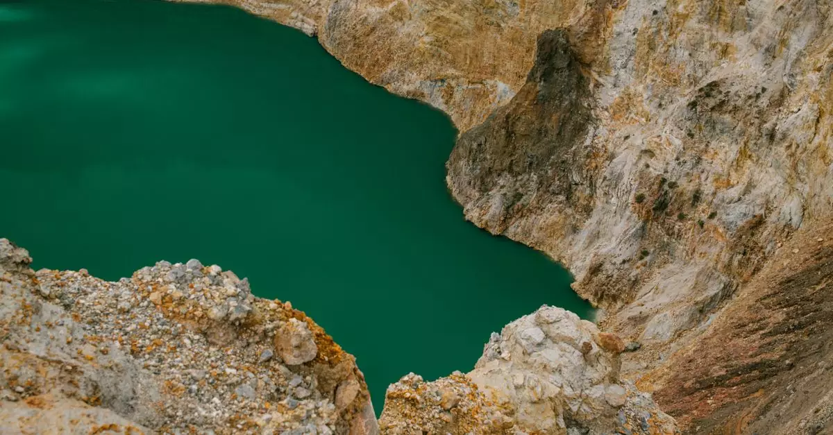 Stunning aerial shot of a bright green crater lake surrounded by rocky formations.