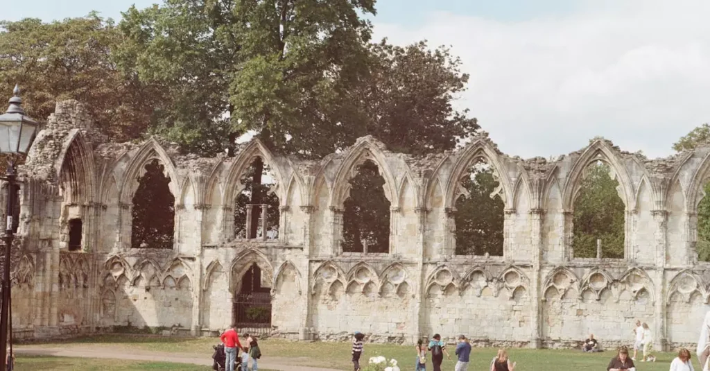 Visitors explore the medieval ruins of St. Mary's Abbey on a sunny day in York, England.
