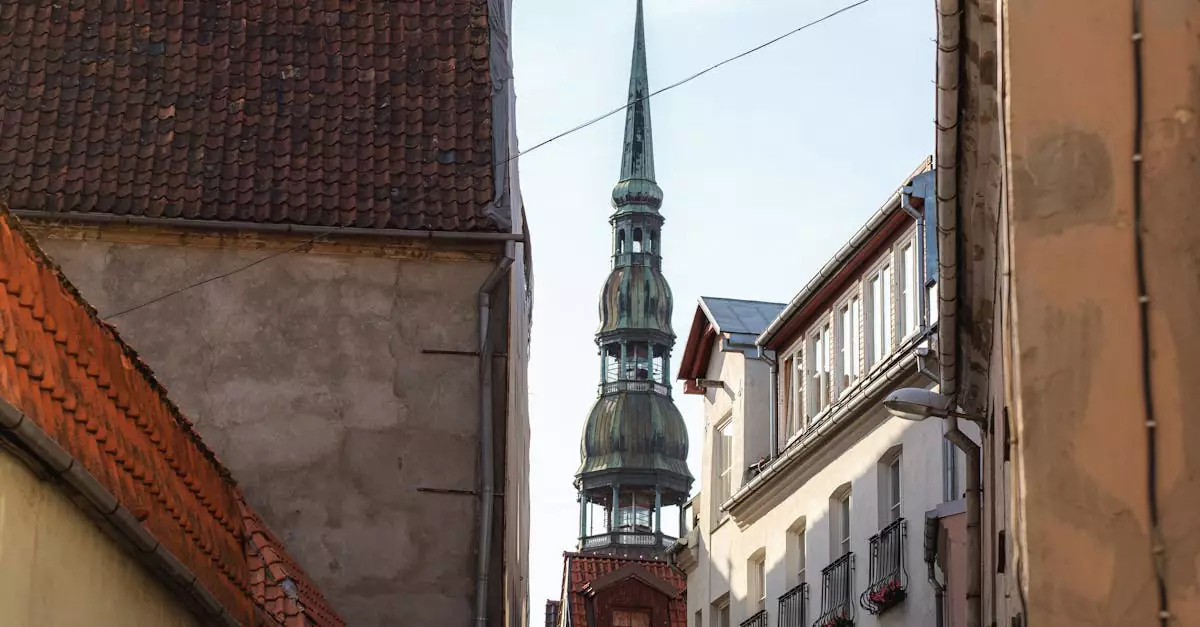 A vertical view of St. Peter's Church spire framed by historic buildings in Riga, Latvia.