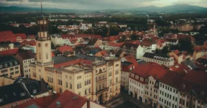 Drone shot of Zittau Town Hall surrounded by red-roofed buildings under cloudy skies.