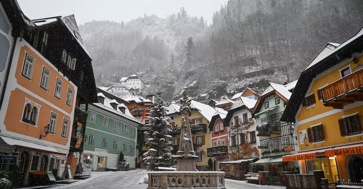 Charming winter view of Hallstatt's colorful town square with snow-covered buildings and a central fountain.
