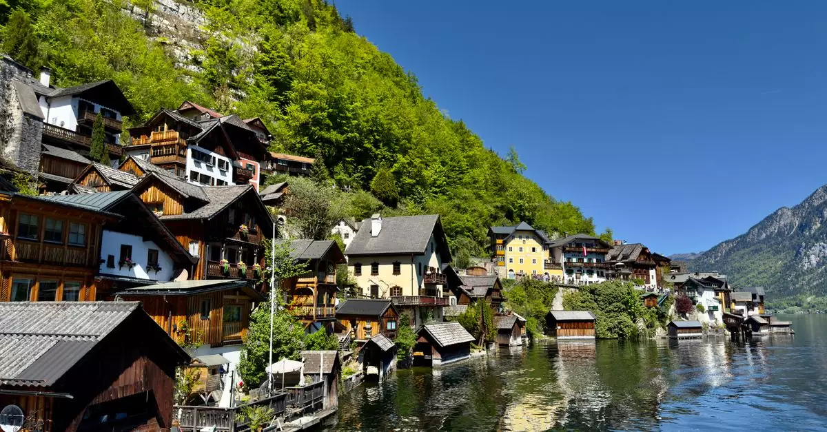 Picturesque Hallstatt with traditional alpine houses reflecting on the lake in sunny weather.