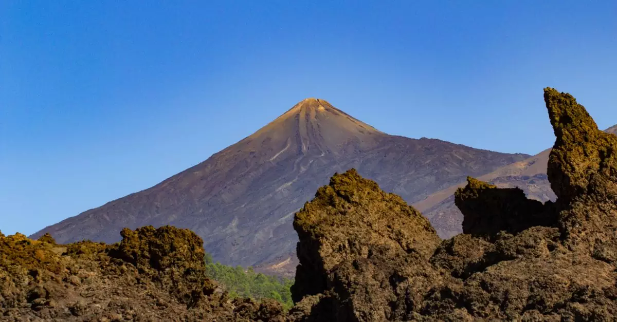 Stunning view of Mount Teide with rugged volcanic terrain under a clear blue sky.
