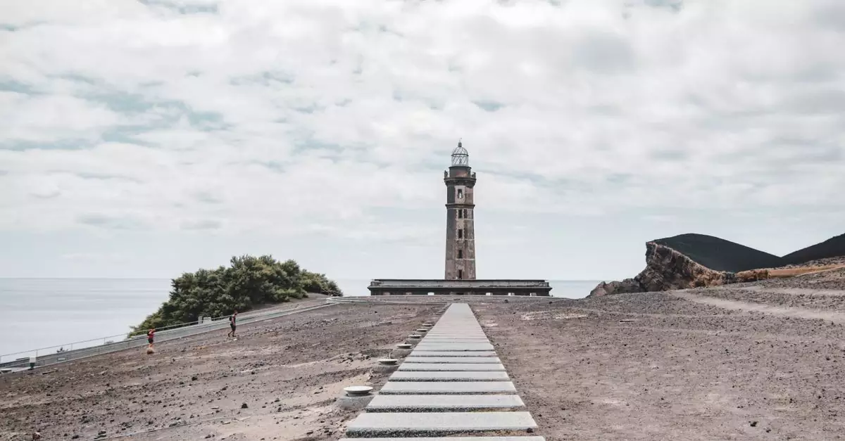 Scenic view of the Capelinhos Lighthouse under a cloudy sky on Faial Island, Azores.