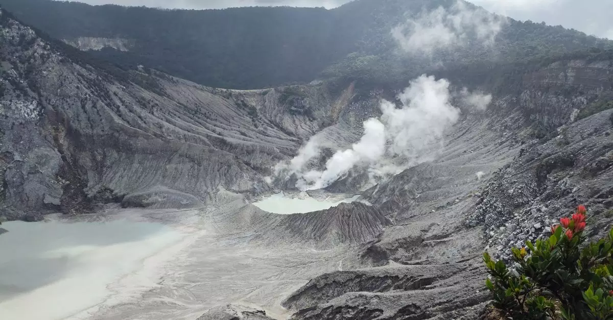 A stunning view of a steaming volcanic crater nestled in mountainous terrain.