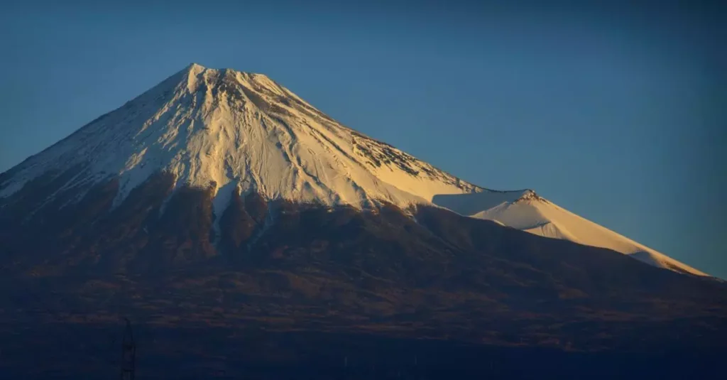 Best Volcano Destinations: Explore Earth's Fiery Wonders 7 A breathtaking view of Mount Fuji covered in snow at sunrise, under a clear blue sky.