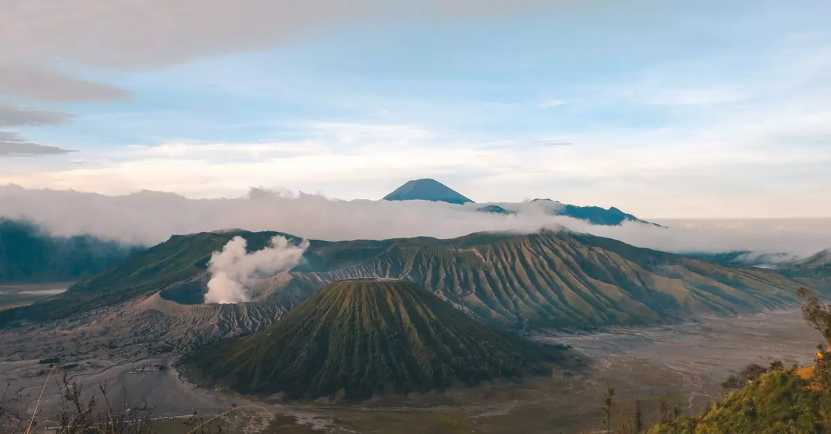 Stunning landscape of Mount Bromo, a famous volcano in East Java, Indonesia, surrounded by mist and rolling hills.