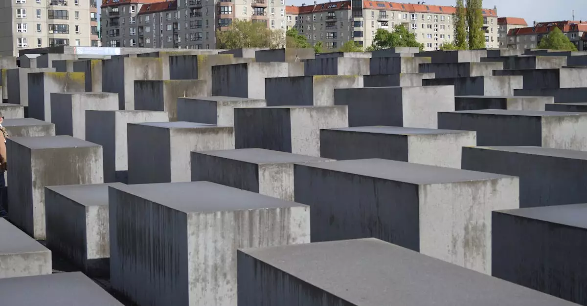 View of the Holocaust Memorial in Berlin, featuring rows of concrete blocks against city buildings.