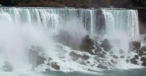 Captivating image of Niagara Falls' powerful cascade during autumn with mist rising.
