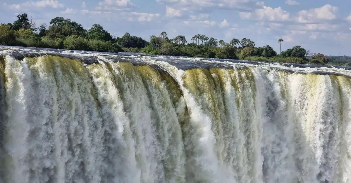 Stunning view of Victoria Falls cascading with vibrant energy, surrounded by lush greenery.