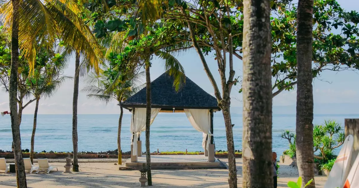 Tropical pavilion with palm trees by the beach in Bali, Indonesia, offering a serene coastal view.