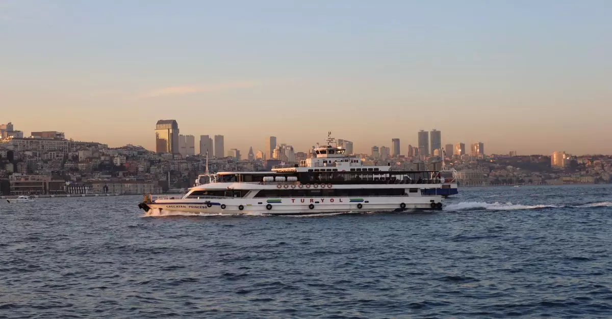 A ferry sails across the Bosphorus with Istanbul's skyline in the background during sunset.