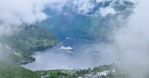 Breathtaking aerial view of Geiranger Fjord in Norway with a cruise ship and lush scenery.