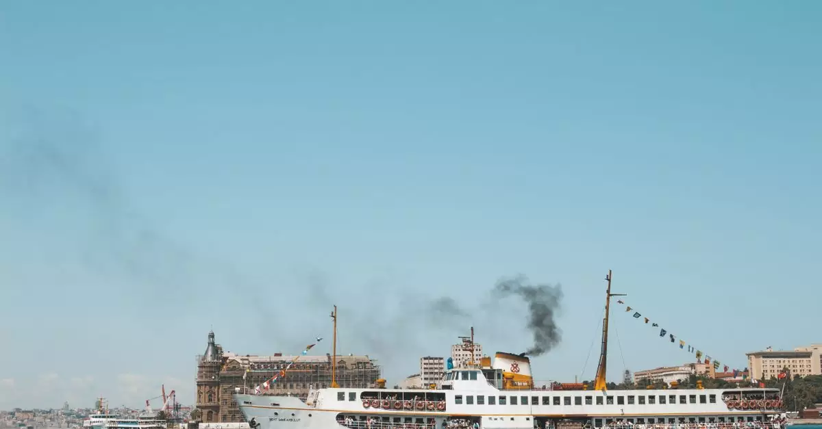 A passenger ferry sails near a distinctive coastal landmark on a clear day.