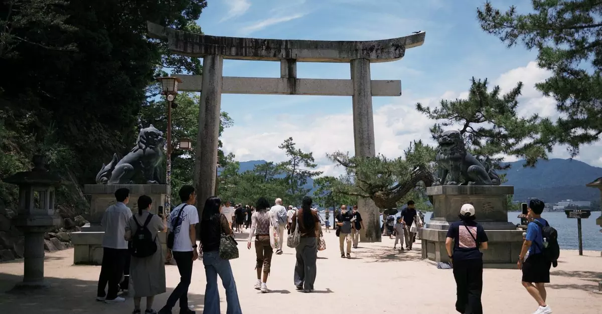 Tourists explore the iconic Torii gate at Itsukushima Shrine in Japan on a sunny day.