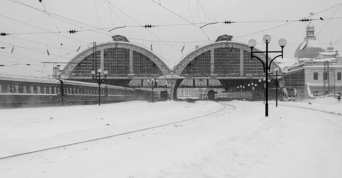 A black and white view of Lviv train station in winter snow, showcasing urban architecture.
