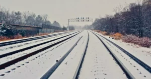Snow-covered railway tracks extending through a winter landscape.