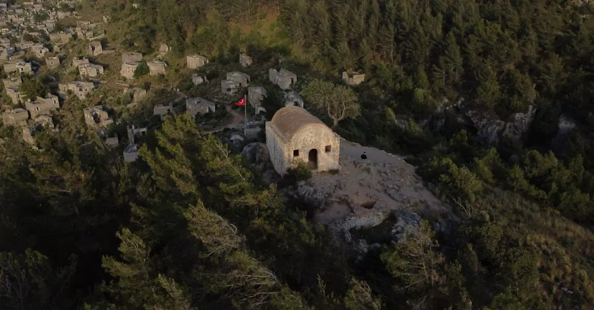 Aerial shot showcasing the historic ruins of Kayak&ouml;y village in Turkey, surrounded by forests.