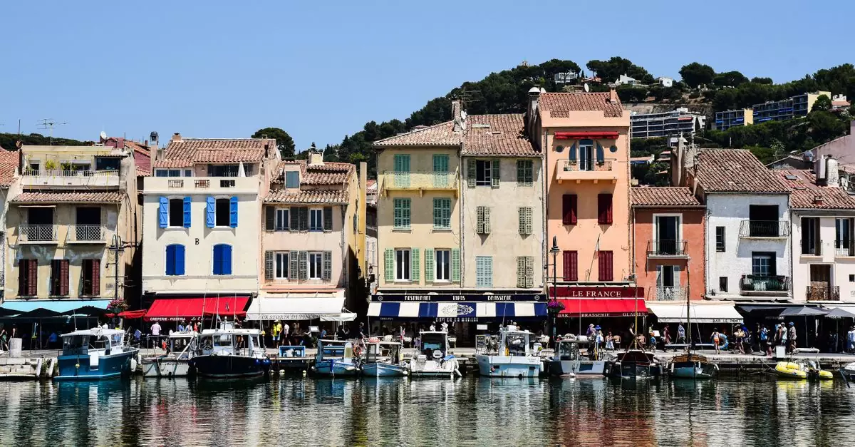 Charming pastel waterfront buildings in Cassis, France, reflecting on the water, showcasing vibrant architecture.