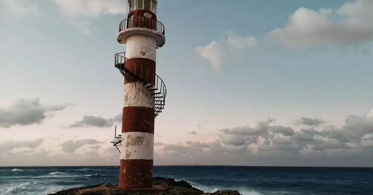 A striking lighthouse on the rocky coast of Cancún under a vivid sky.