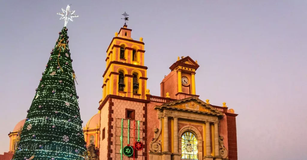 Cozumel Christmas Travel Guide: Festive Island Fun 2 Beautifully decorated Christmas tree beside a historic church in Tequisquiapan, Mexico during sunset.