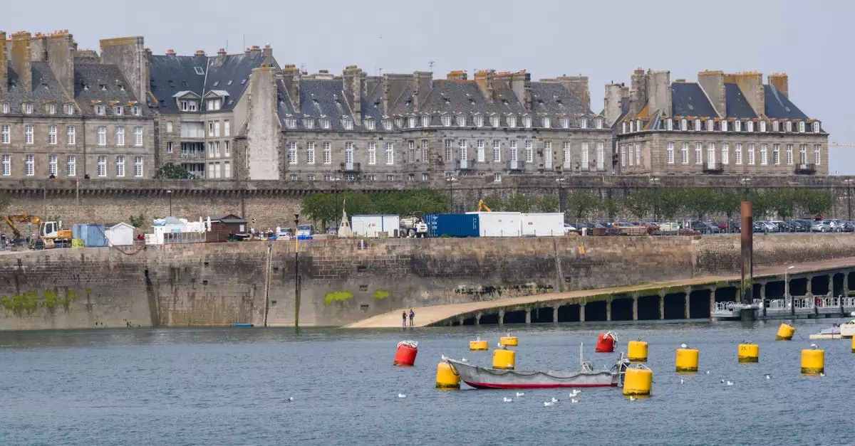 Scenic view of Saint-Malo's historic architecture along the harbor, with colorful buoys and boats in the foreground.
