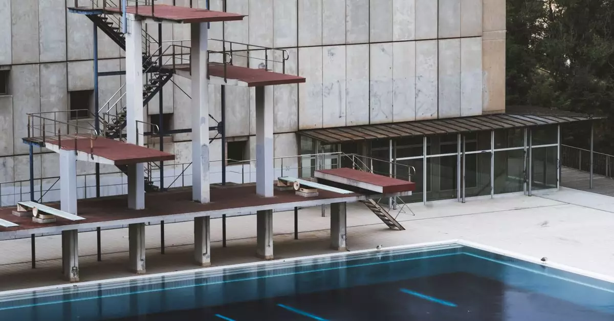 Empty swimming pool with diving platforms in Barcelona, showcasing urban decay.