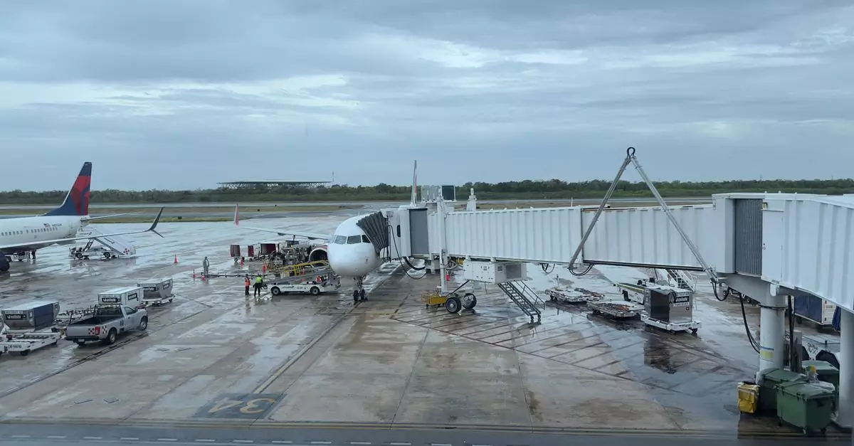 Commercial airplanes at a rainy airport terminal with jet bridge and ground crew.