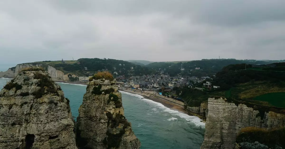 Scenic aerial view of the famous &Eacute;tretat cliffs and coastline on a cloudy day, showcasing the town's unique landscape.
