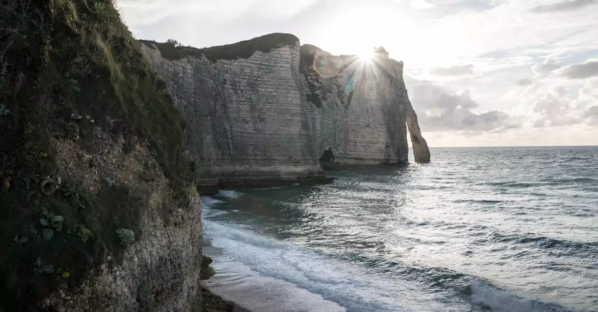 Sunlit cliffs of &Eacute;tretat with waves crashing against the shore in Normandy, France.