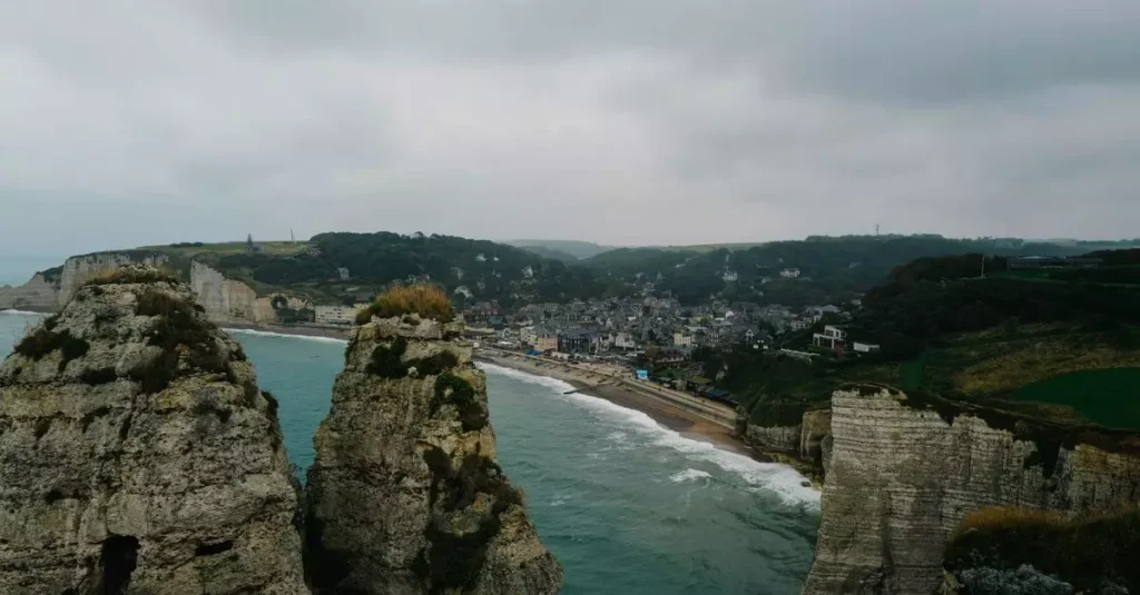 Etretat France Romantic Travel Guide: Coastal Escapes 2 Scenic aerial view of the famous Étretat cliffs and coastline on a cloudy day, showcasing the town's unique landscape.