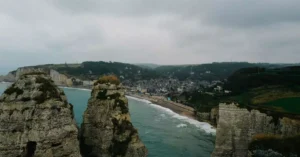Scenic aerial view of the famous Étretat cliffs and coastline on a cloudy day, showcasing the town's unique landscape.