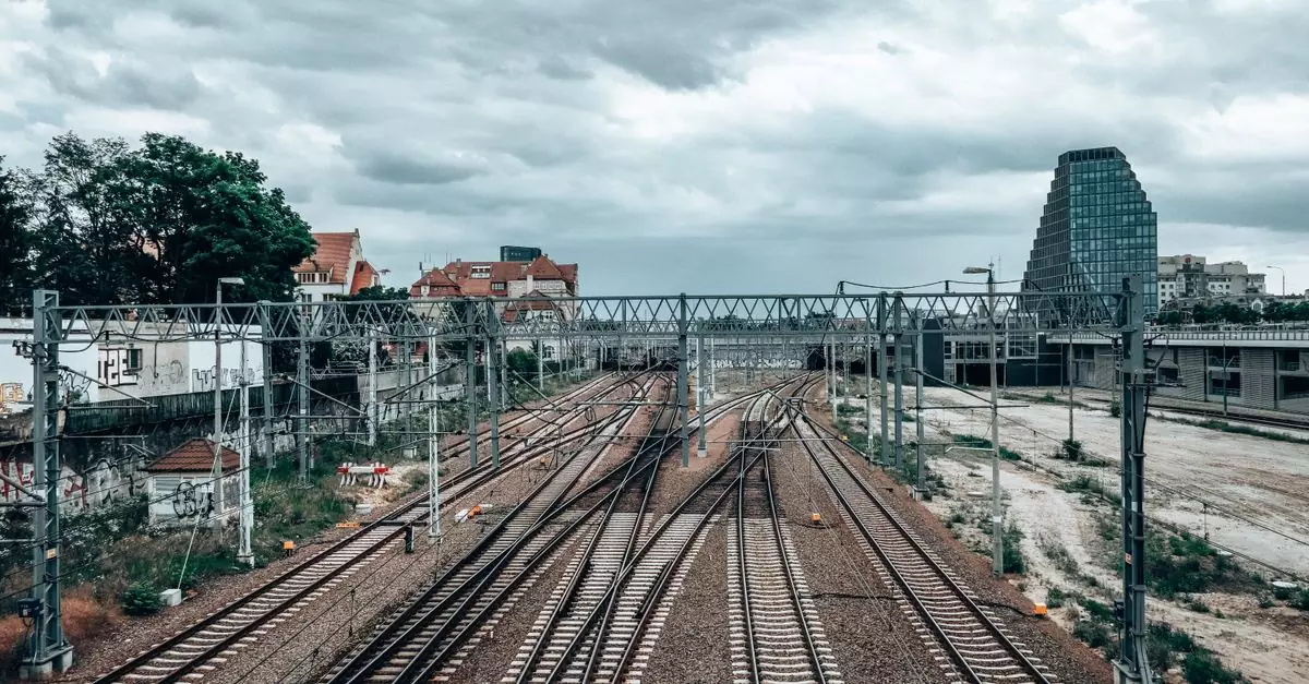 View of railway tracks and urban landscape in Poznań, Poland, under a cloudy sky.