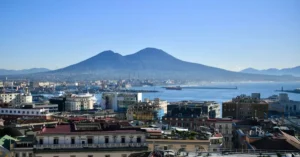 Aerial view of Naples, Italy with Mount Vesuvius in the background, capturing the vibrant coastal cityscape.