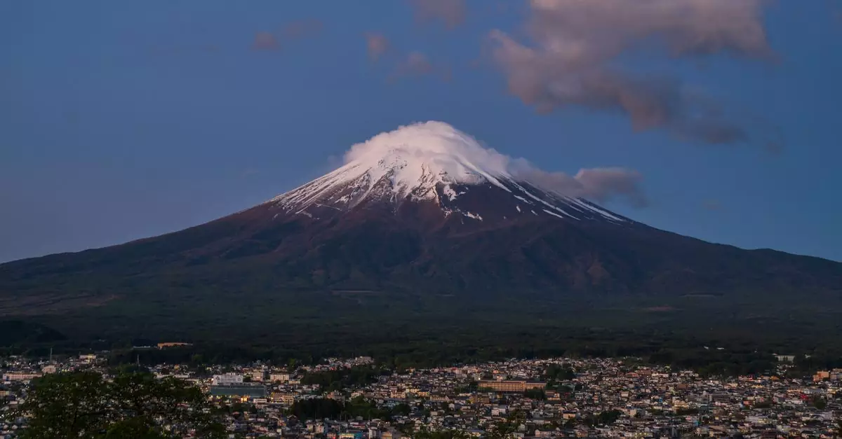 Scenic twilight view of Mount Fuji with a cityscape in the foreground.