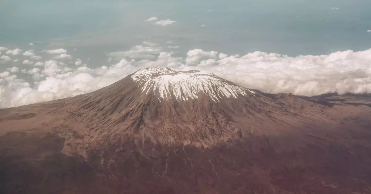 Breathtaking aerial view of Mount Kilimanjaro's snow-capped peak surrounded by clouds.