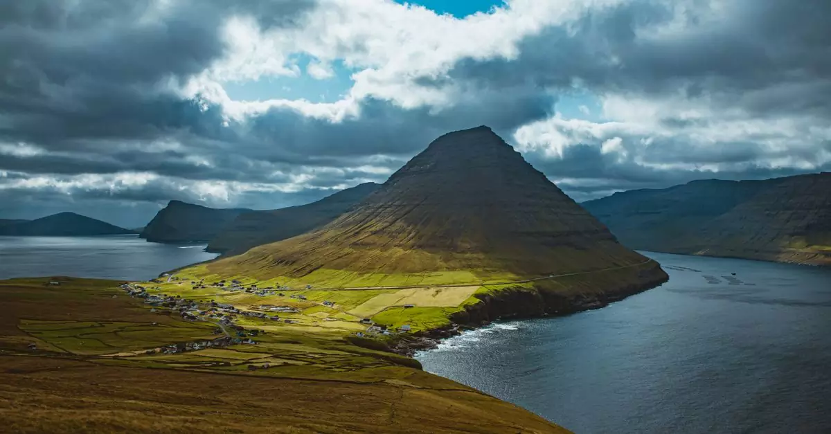 A stunning drone shot of the majestic Faroe Islands landscape featuring mountains, sea, and villages.