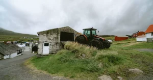 Scenic rural view of a Faroe Islands village with a red tractor and traditional architecture.
