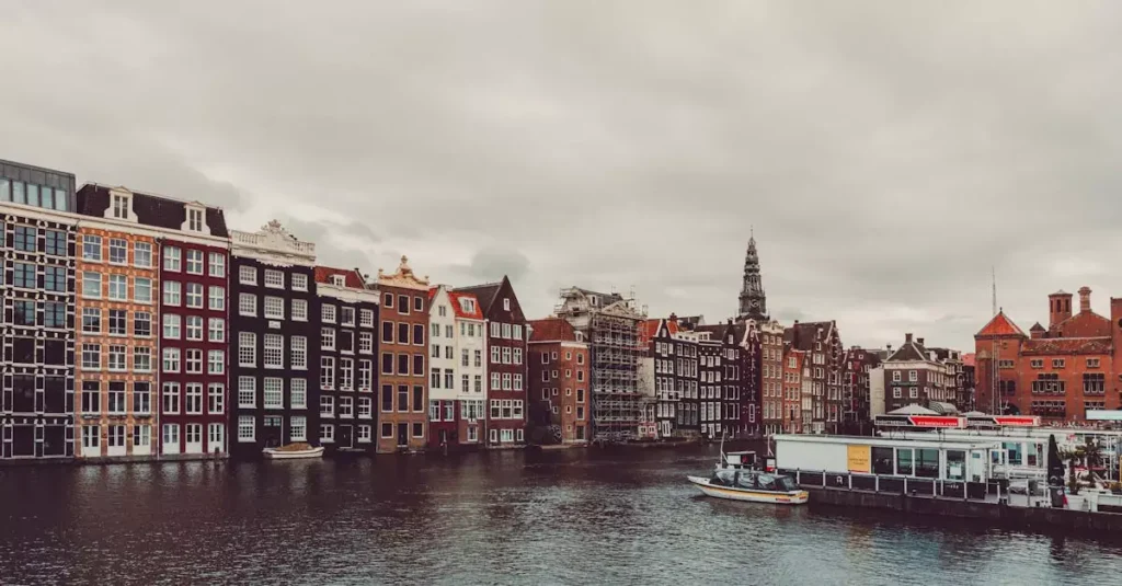 First Trip to Amsterdam Tips: Your Essential Guide 2 Charming Amsterdam canal and traditional houses with cloudy sky.