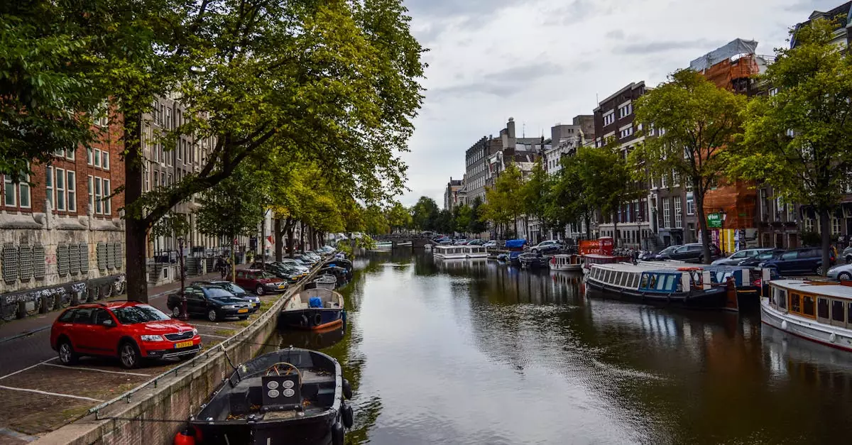Various cruise boats moored on canal flowing in aged city between typical buildings against cloudy sky