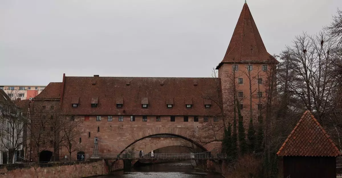 Medieval building on the Pegnitz River, Nuremberg, showcasing Gothic architecture on a cloudy day.