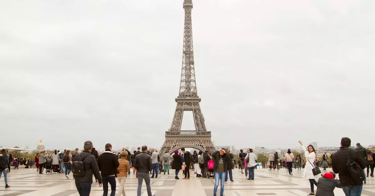 Crowd of tourists at the iconic Eiffel Tower in Paris on an overcast day.