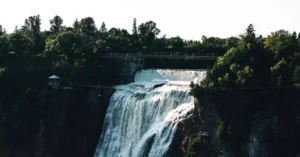 Stunning view of Montmorency Falls in Québec surrounded by lush greenery and a pedestrian bridge.