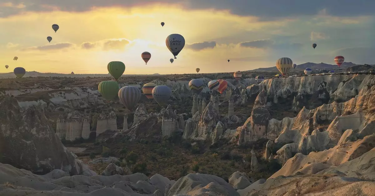 Stunning view of hot air balloons floating over Cappadocia's unique landscape at sunset.