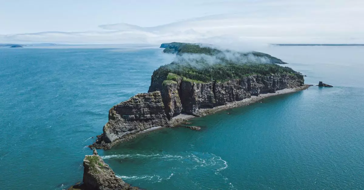 From above of bristly rock on rippled sea with horizon under cloudy sky in mist