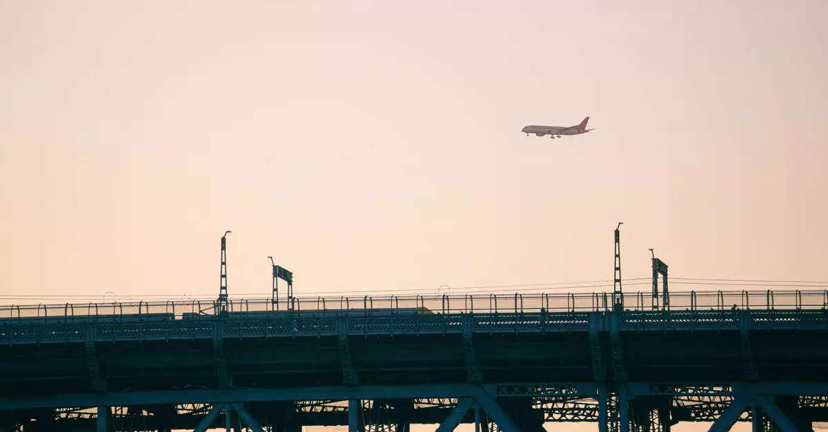 A plane flies over an urban bridge at sunset, creating a stunning silhouette.