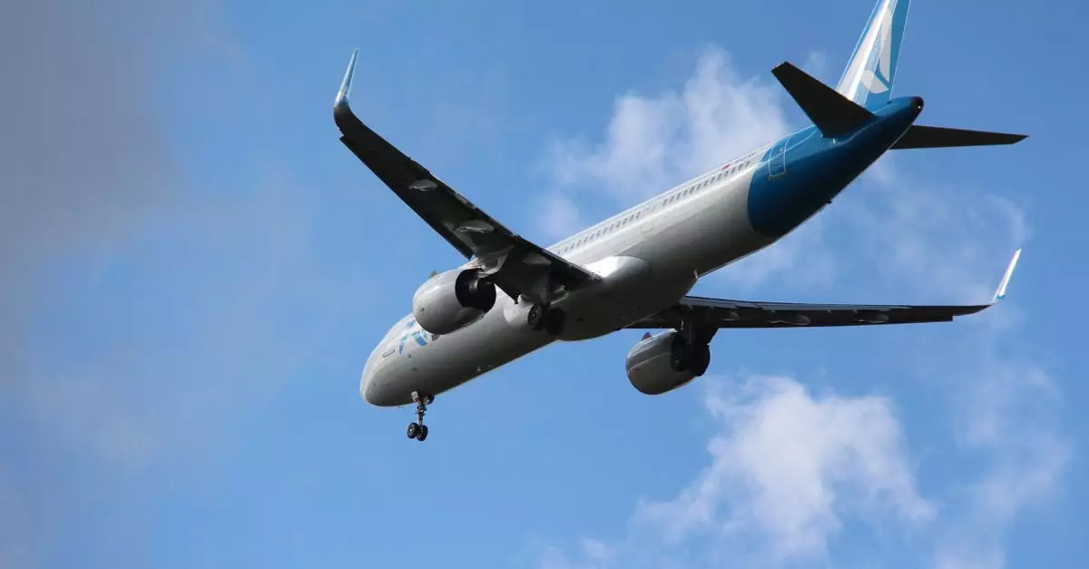 A commercial airplane flying against a clear blue sky, photographed in Amsterdam, Netherlands.