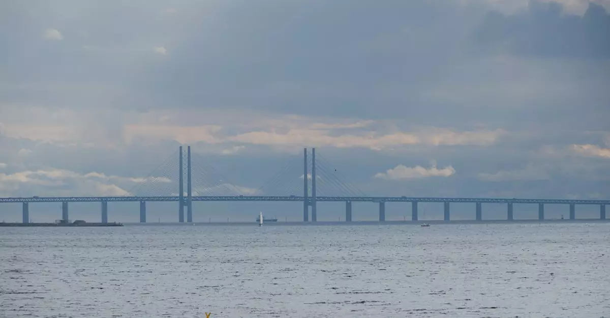 The &Oslash;resund Bridge spans across a serene sea under overcast skies, creating a breathtaking view.
