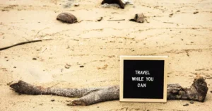 Motivational sign on sandy beach prompts travelers to seize the moment. Perfect for travel inspiration.
